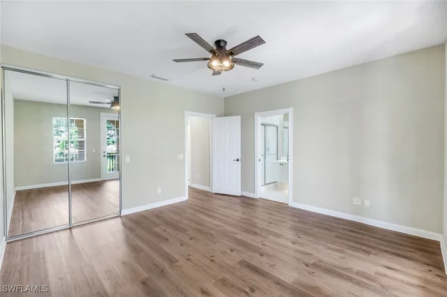 a view of an empty room with wooden floor and a ceiling fan