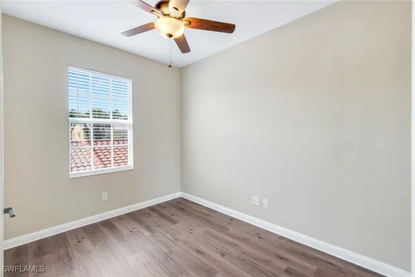an empty room with a window and a fan
