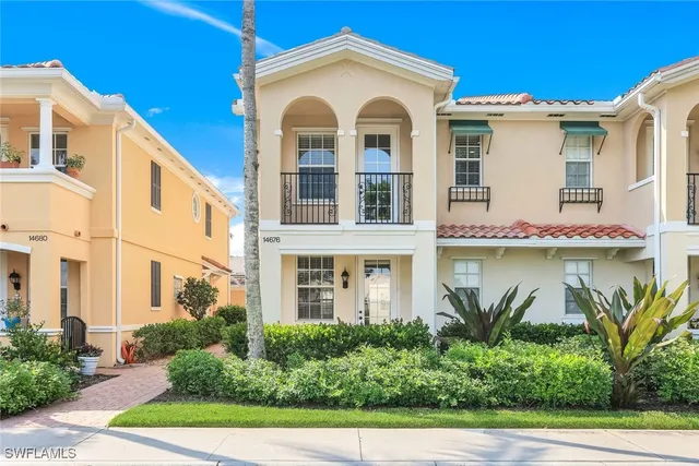 a view of a white house with large windows and a table and chairs