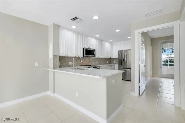 a view of kitchen with stainless steel appliances refrigerator sink and cabinets