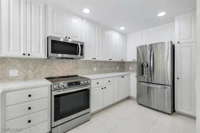 a kitchen with white cabinets and stainless steel appliances