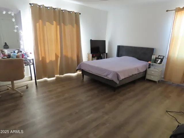 a bedroom with a bed a chair and a large window