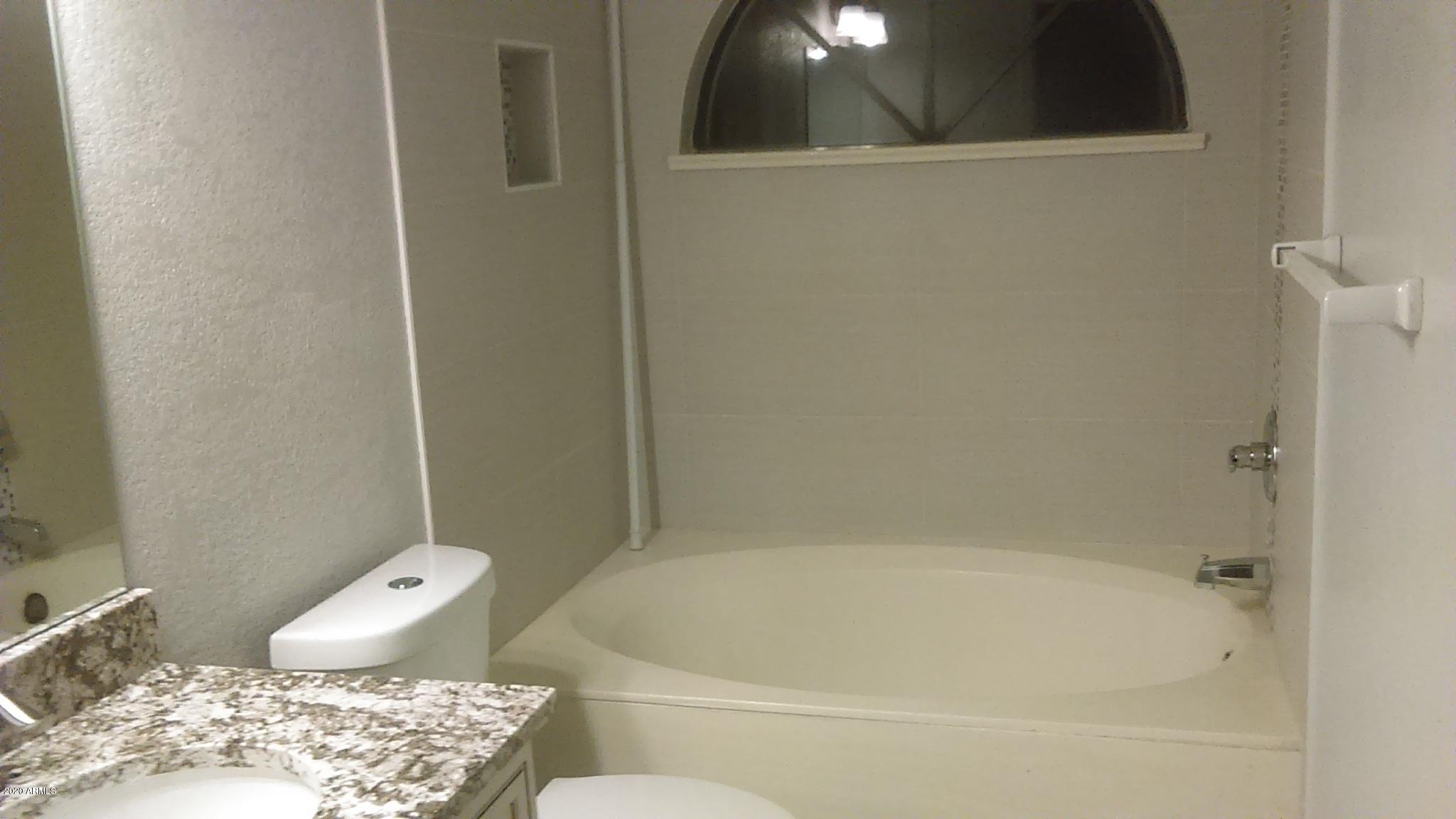 5640 East Bell Road, Unit 1022 Scottsdale, AZ 85254 - Photo 3 of 27 a bath tub sitting next to a toilet and a sink