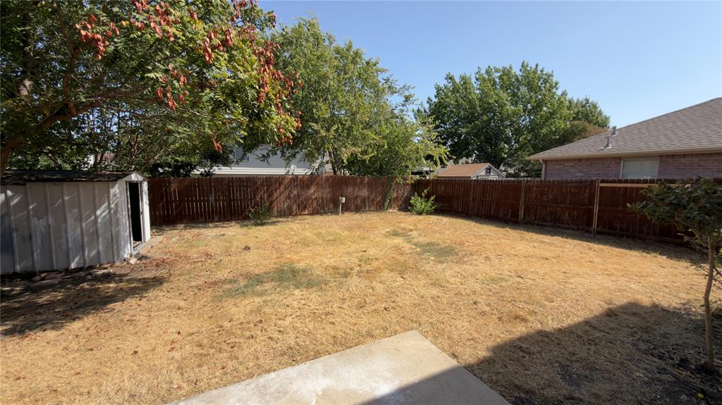 3401 Cheyenne Ranch Road Fort Worth, TX 76262 - Photo 16 of 17 Expansive backyard featuring a wood privacy fence, mature trees, and a storage shed