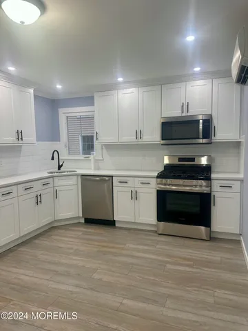 an empty room with wooden floor cabinet and windows