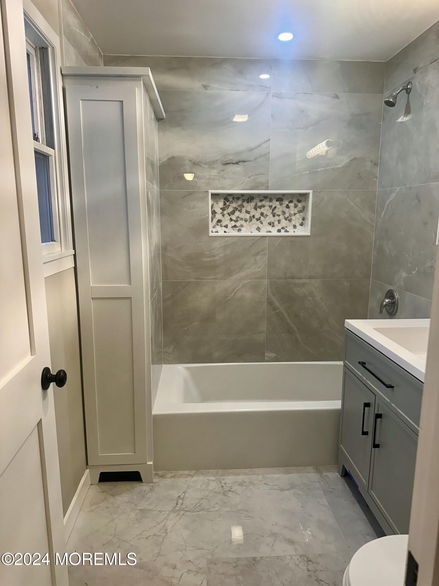 73 Church Street Manasquan, NJ 08736 - Photo 19 of 27 a bathroom with a tub a sink and a mirror