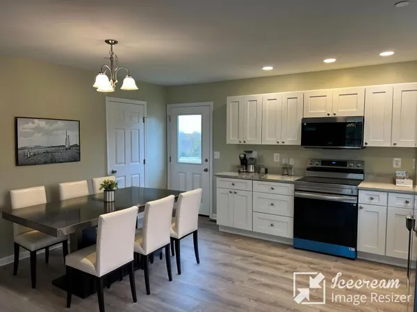 a kitchen with stainless steel appliances granite countertop a stove a sink a microwave a dining table and chairs