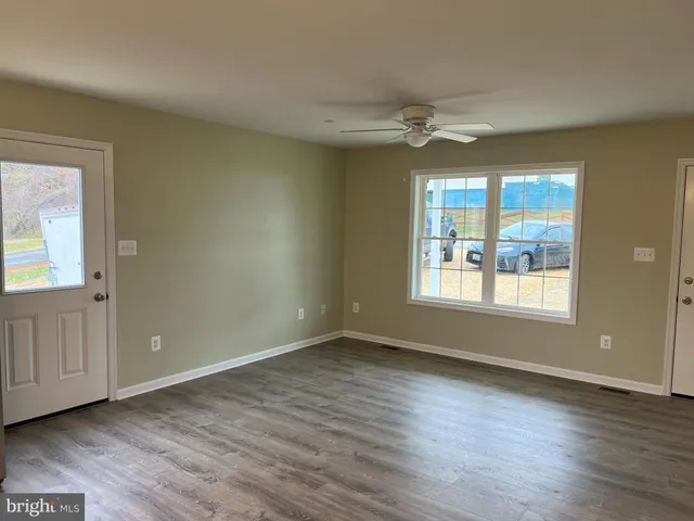 a view of an empty room with a window and wooden floor