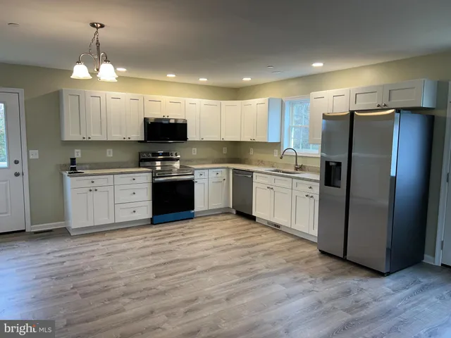 a kitchen with stainless steel appliances granite countertop a refrigerator a sink a stove a microwave and a refrigerator