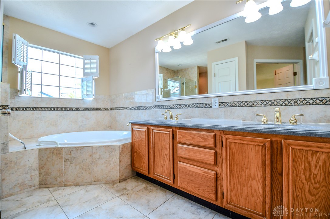 3915 East Summit Ridge Drive Beavercreek, OH 45430 - Photo 27 of 47 This primary bathroom features a corner soaking tub and an expansive vanity with double sinks.