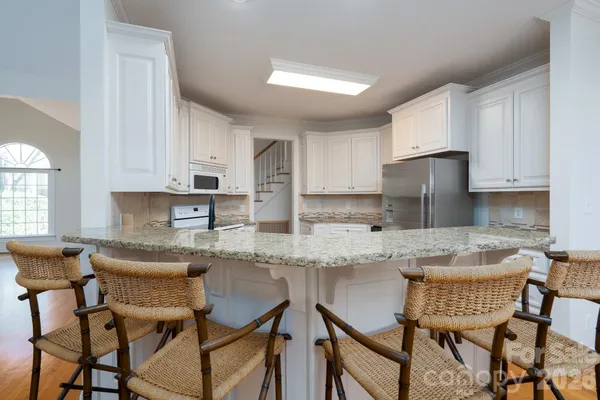 a kitchen with stainless steel appliances granite countertop a table and chairs in it