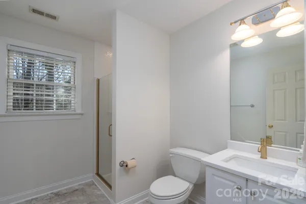 a bathroom with a granite countertop toilet sink and mirror