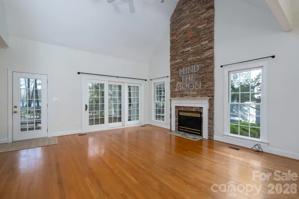 a view of an empty room with wooden floor fireplace and a window