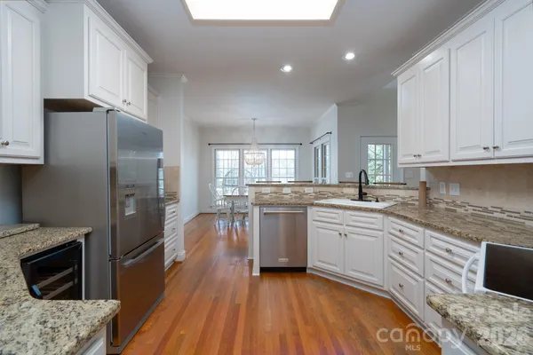 a kitchen with a sink dishwasher a refrigerator and a stove with wooden floor
