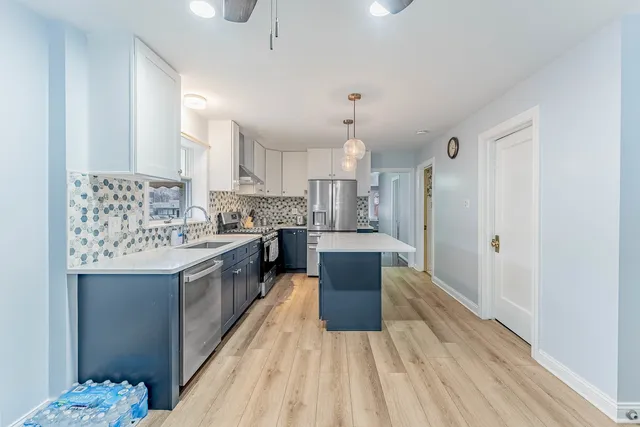 a large kitchen with a center island wooden floor stainless steel appliances and cabinets