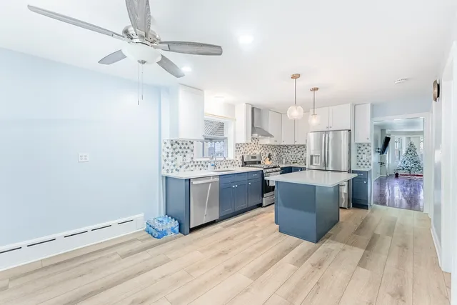 a kitchen with stainless steel appliances kitchen island hardwood floor sink and stove