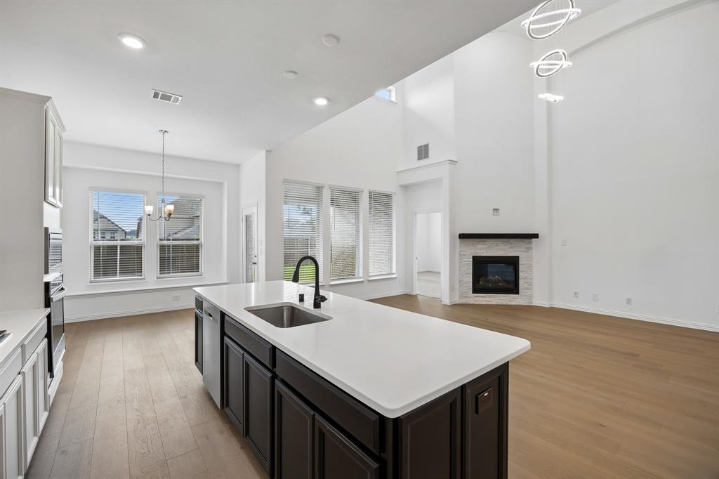 1303 Wheelwright Drive Forney, TX 75126 - Photo 15 of 39 Contemporary kitchen island with an integrated sink and matte black faucet, featuring a light countertop and dark cabinetry