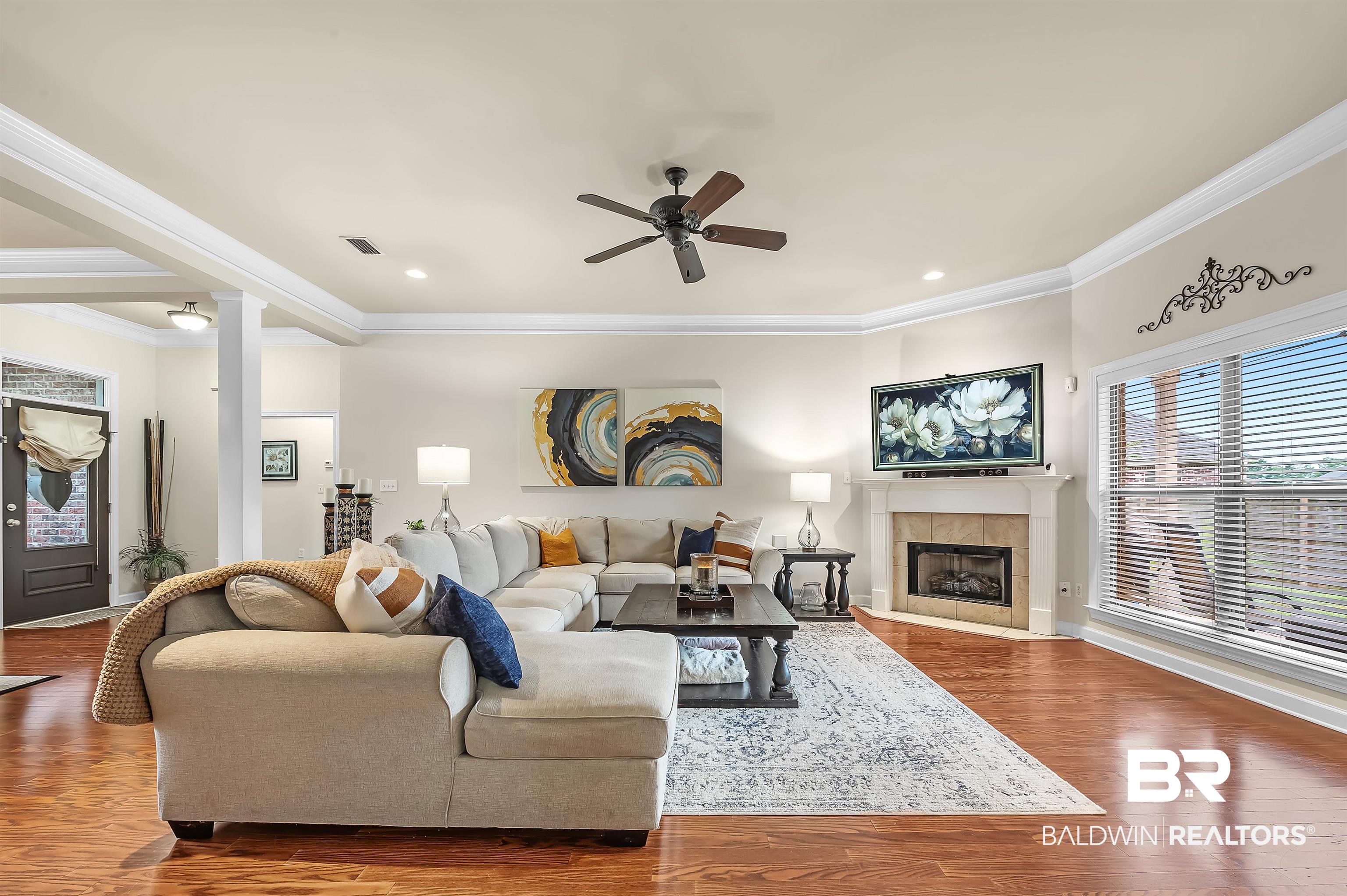 9376 Sable Court Daphne, AL 36526 - Photo 10 of 46 Living room featuring hardwood / wood-style floors, ceiling fan, a fireplace, and crown molding