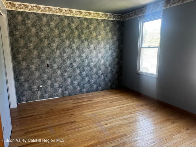 a view of an empty room with window and wooden floor