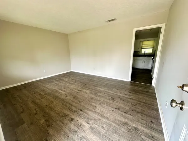 a view of an empty room with a window and wooden floor