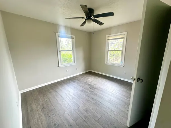an empty room with wooden floor and windows