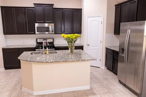 a kitchen with granite countertop a refrigerator a stove a sink and dishwasher