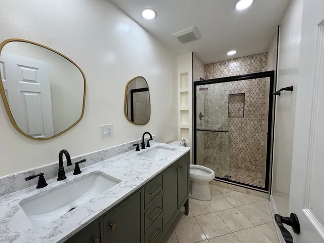 a bathroom with a granite countertop sink a toilet a mirror and shower