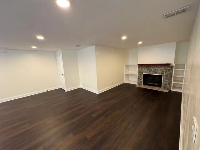 an empty room with wooden floor and fireplace