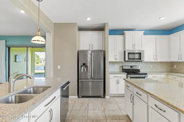 a kitchen with a sink a center island a stove and a chandelier