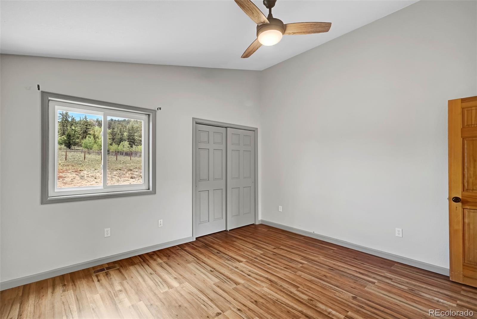 2491 Stagestop Road Jefferson, CO 80456 - Photo 14 of 46 an empty room with wooden floor chandelier fan and windows