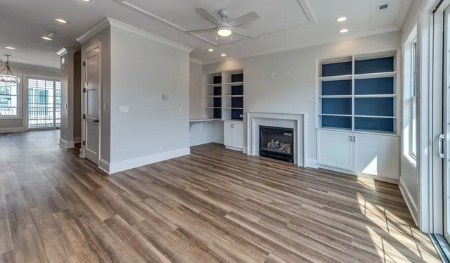 a view of an empty room with wooden floor fireplace and a window