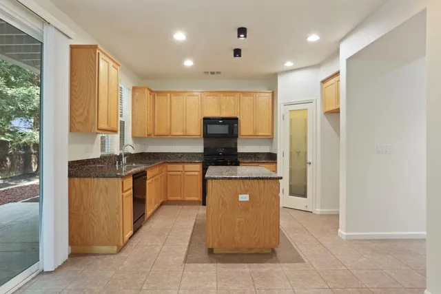 a large kitchen with stainless steel appliances granite countertop a refrigerator and a sink
