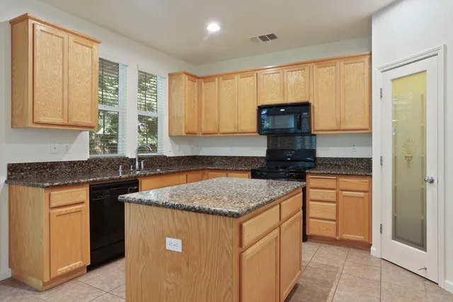 a kitchen with stainless steel appliances granite countertop a stove a sink and a microwave