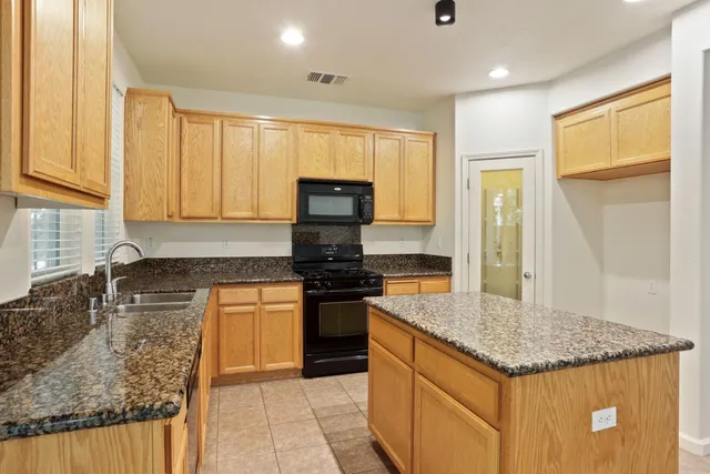 a kitchen with stainless steel appliances granite countertop a stove a sink dishwasher and a refrigerator