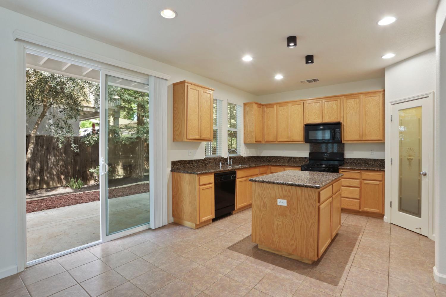 9363 Vintner Circle Patterson, CA 95363 - Photo 18 of 52 a kitchen with stainless steel appliances granite countertop a refrigerator a sink a stove top oven and a view of living room