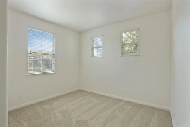 a view of an empty room with closet and a window