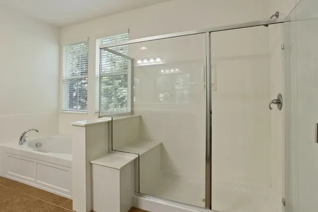 a spacious bathroom with a tub sink and a mirror