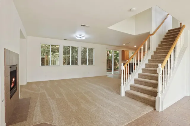 a view of an empty room with wooden floor and a fireplace