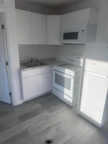 a kitchen with granite countertop white cabinets and stainless steel appliances