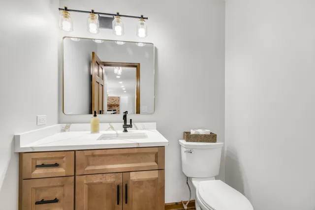 a bathroom with a toilet sink vanity and mirror