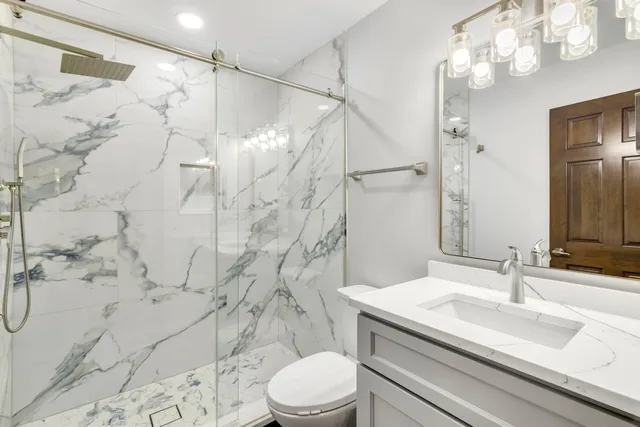 a bathroom with a sink toilet vanity and shower