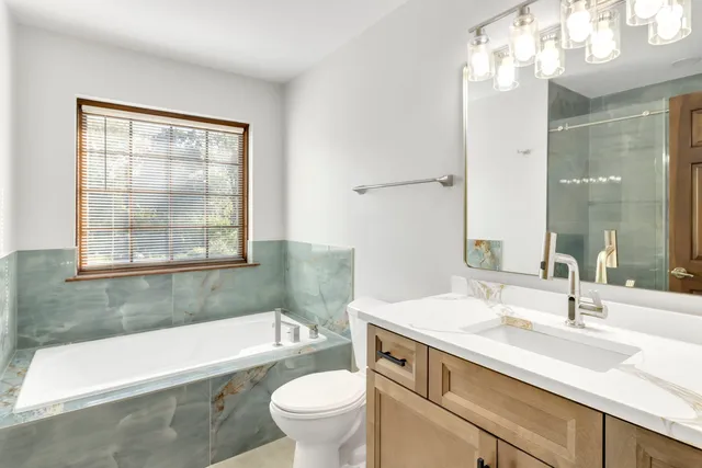 a bathroom with a granite countertop sink a large mirror and a bathtub