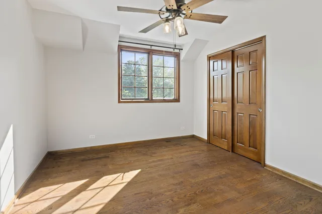 an empty room with chandelier fan and windows