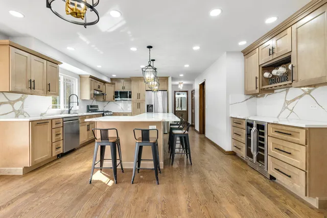 a kitchen with stainless steel appliances kitchen island granite countertop a stove a sink a dining table and chairs with wooden floor