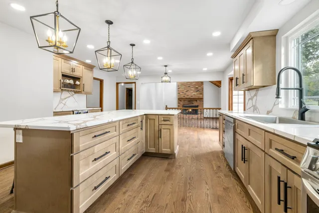 a large kitchen with granite countertop a large counter top a sink appliances and cabinets