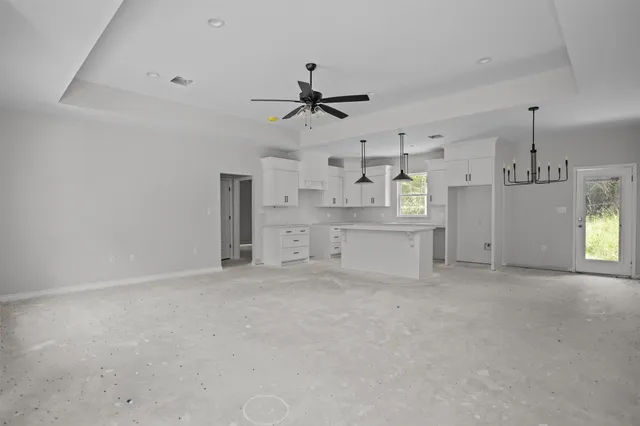 an empty room with windows and ceiling fan