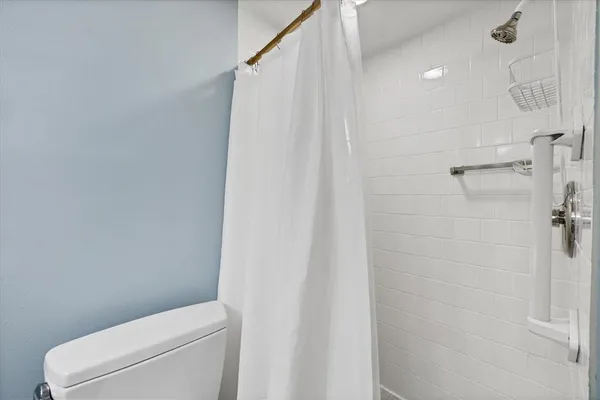 a white toilet sitting next to a shower