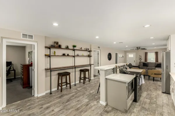 a view of a kitchen with kitchen island stainless steel appliances wooden floor dining table and chair