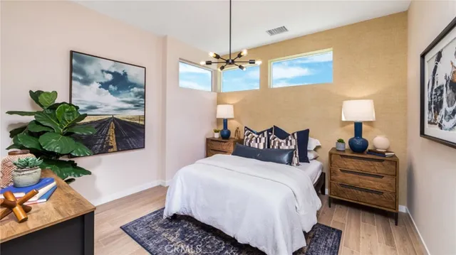 a bedroom with a bed dresser and a chandelier