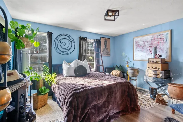 a bedroom with a bed table flowerpot and window